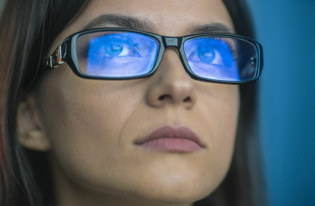 A woman with blue light reflected on her glasses from a screen