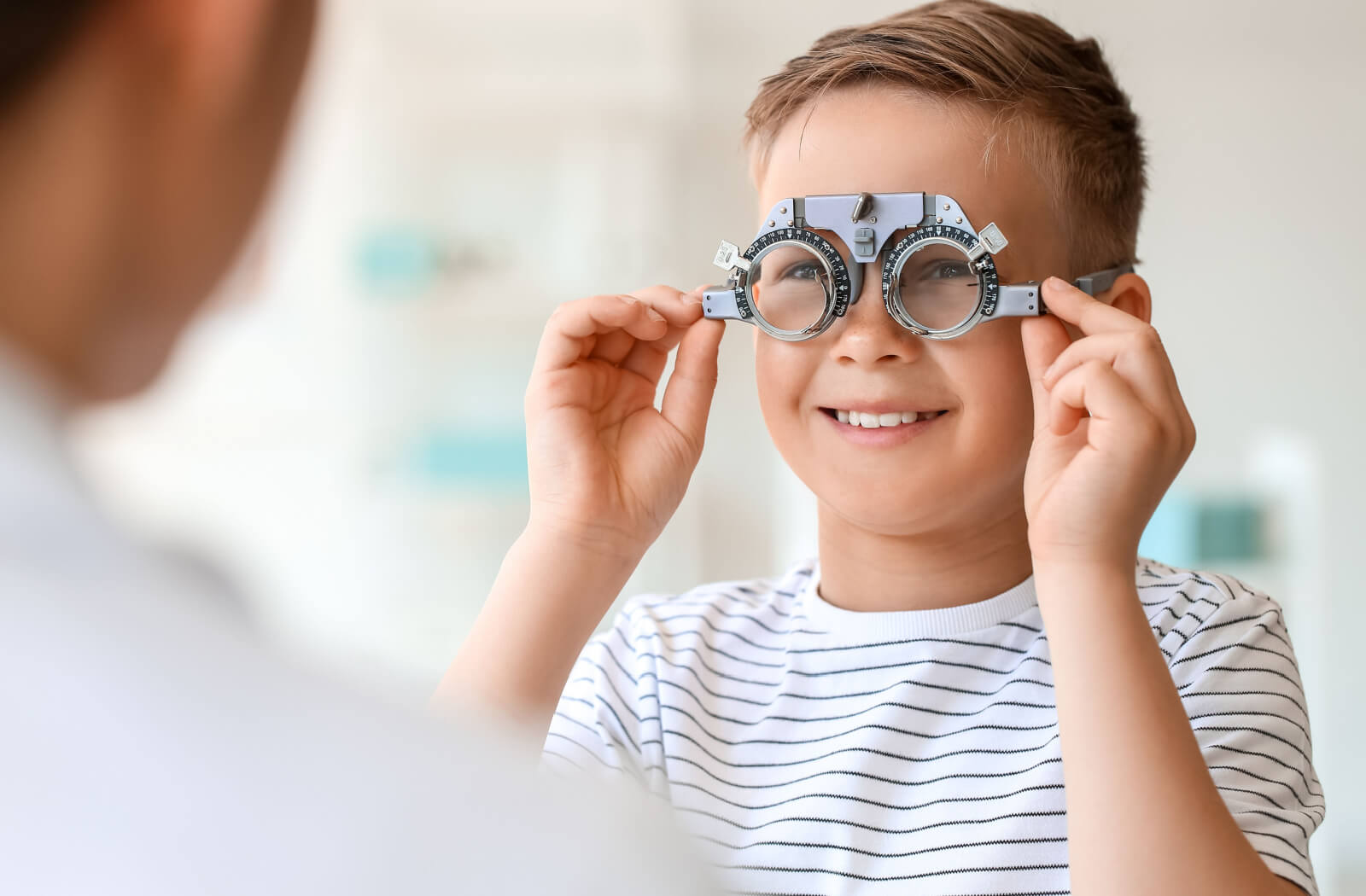 A young boy tests his vision through a lens tool at his eye doctor's office