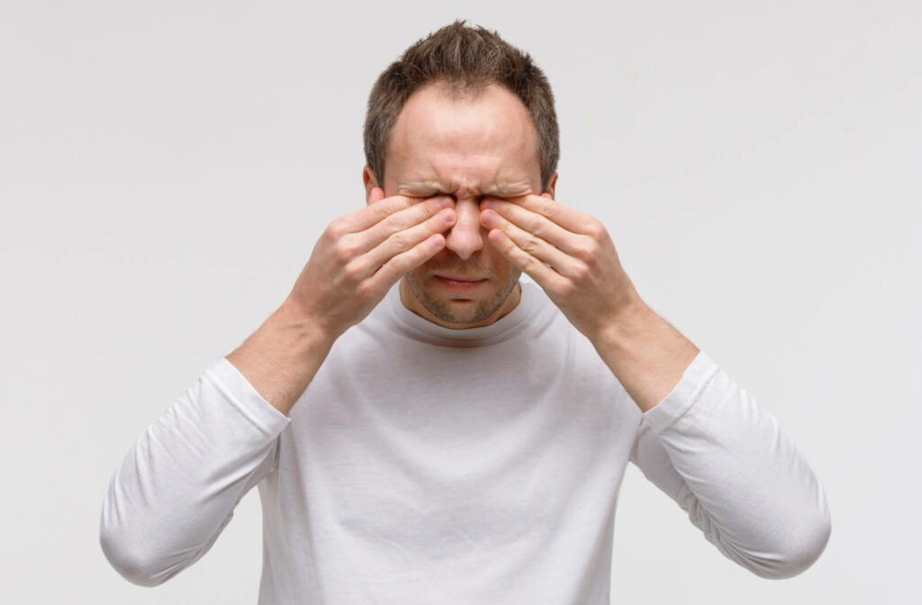 A man rubbing his irritated, dry eyes as he tries to clear his blurry vision.
